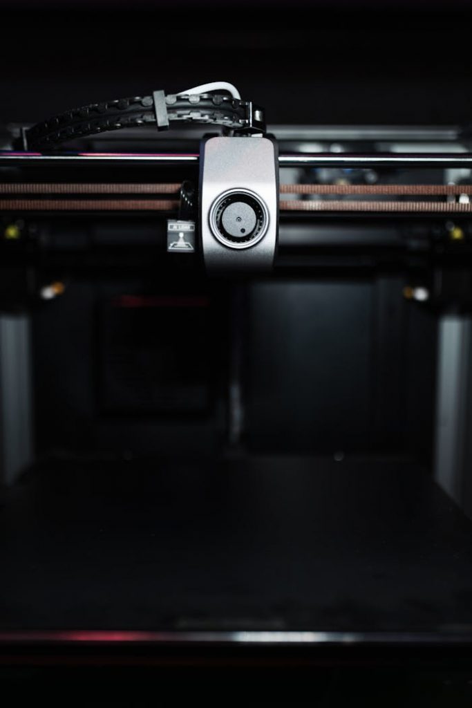 Close-up of a high-precision industrial 3D printer nozzle in a dark setting, showcasing advanced technology.